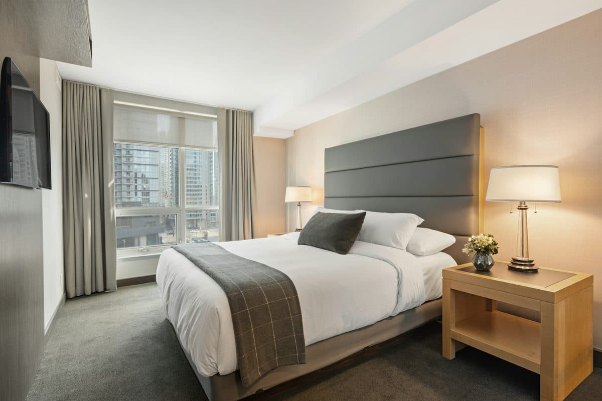 Small bedroom with a made bed, a nightstand, and a lamp