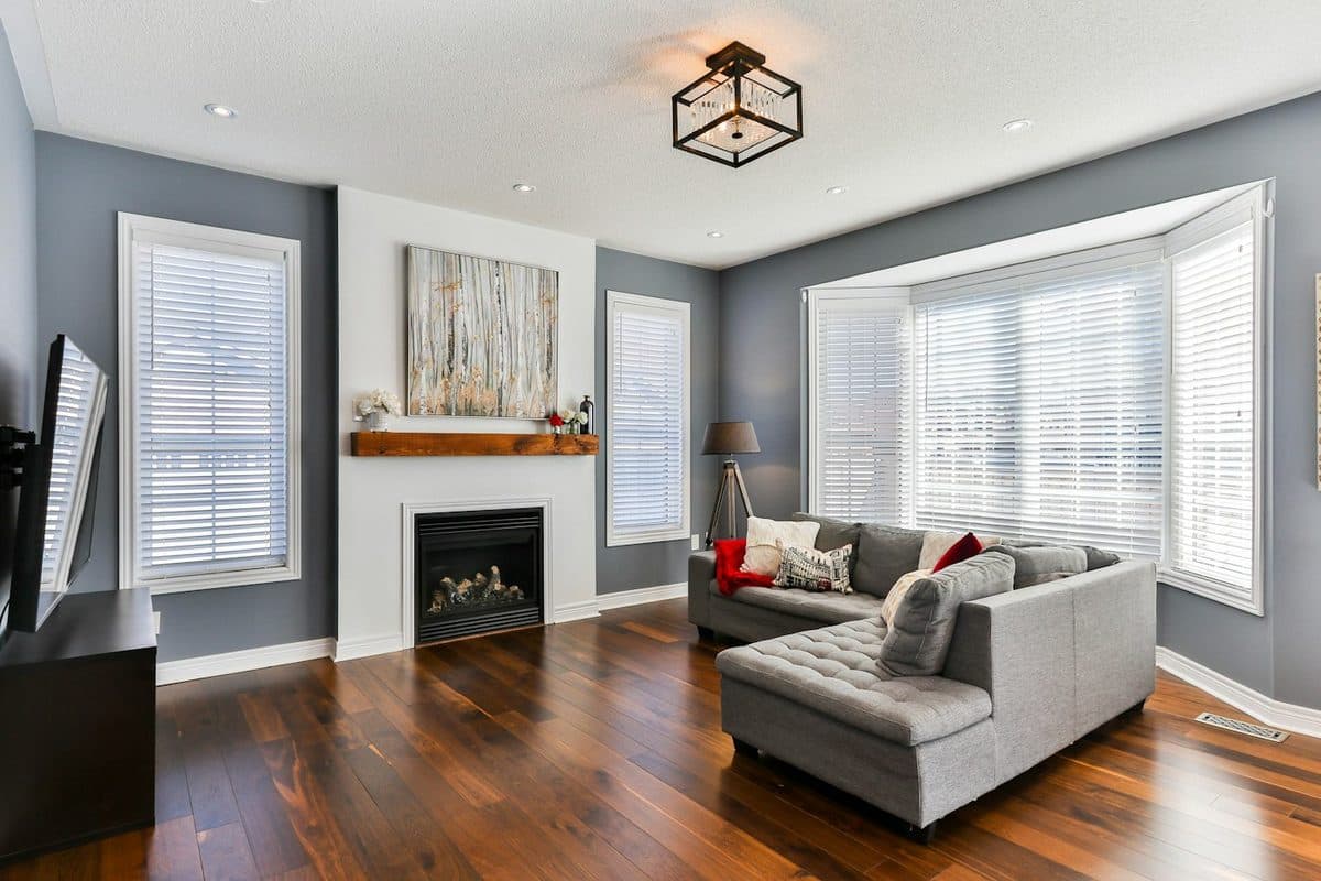 Living room with a gray sectional, a fireplace, a television, and an open wood floor