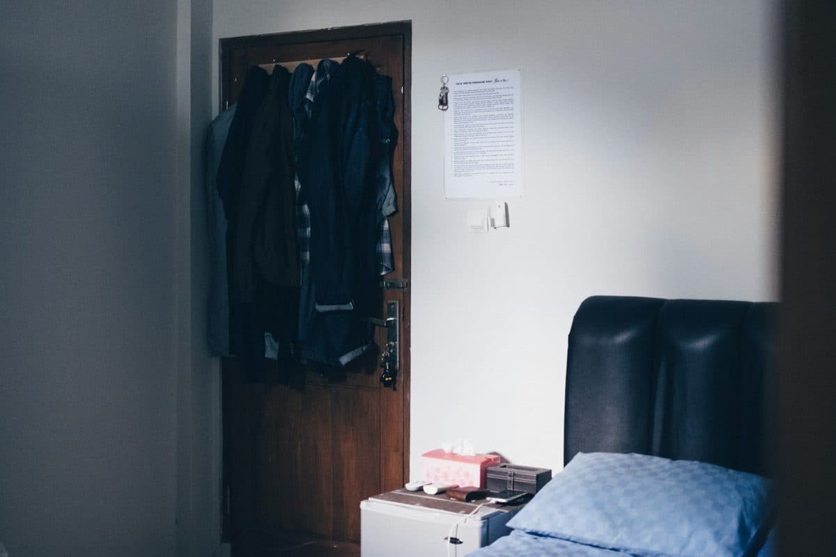 Jackets hanging on hooks over a bedroom door, a no-drill way to keep clothes off the floor