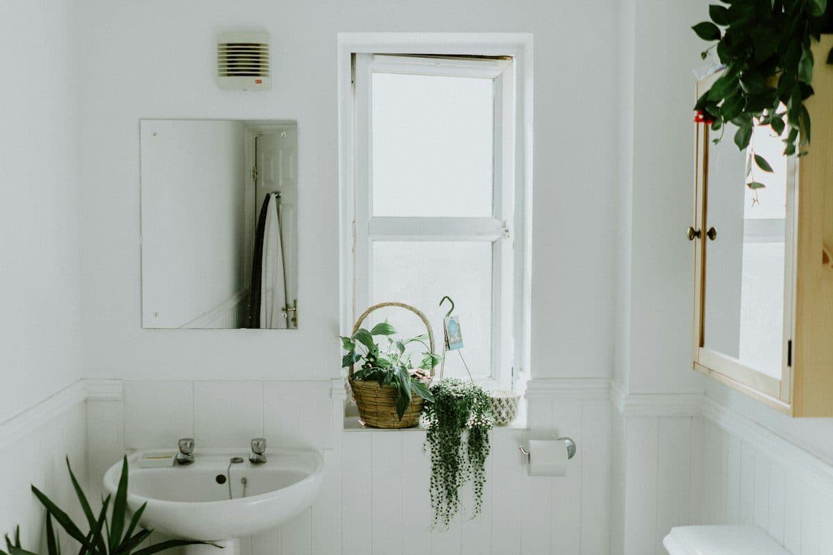 Small white bathroom with a sink, a window, and a wood medicine cabinet