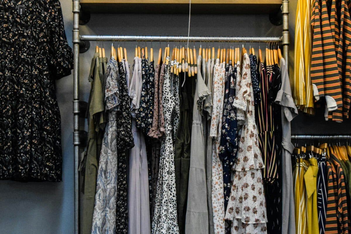 Small rental closet organized with slim matching hangers, a hanging rod extender, labeled shelf bins, and a shoe rack on the floor